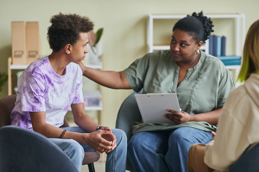 A Black female psychologist attentively advising a young person in a supportive session